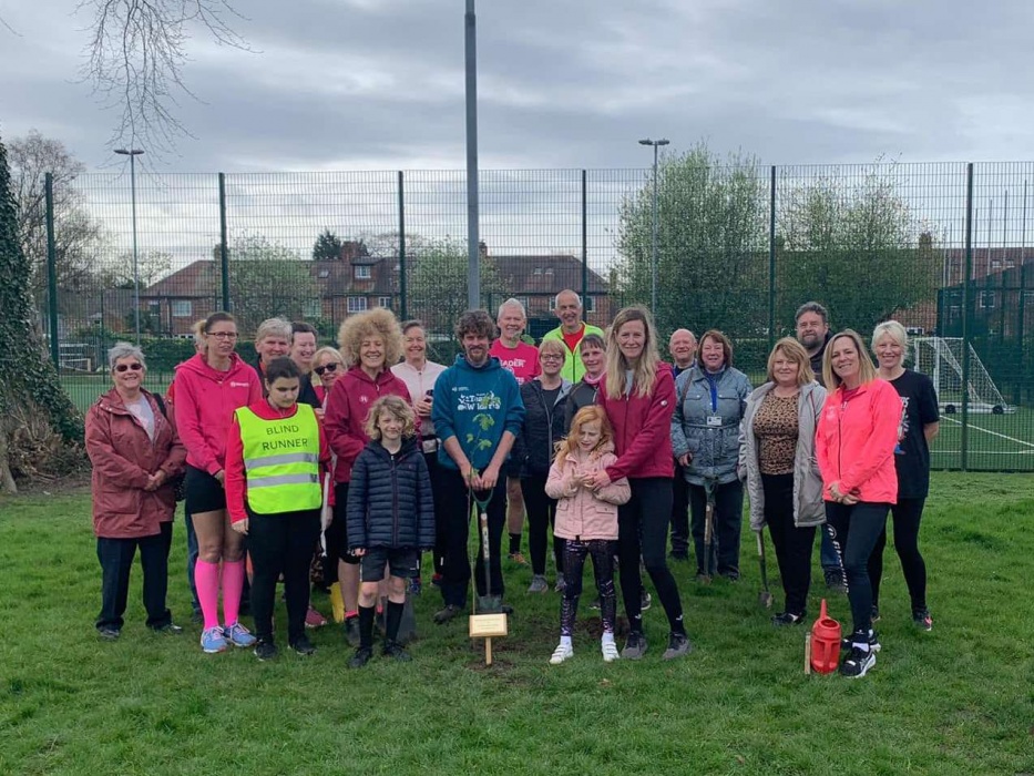 A group of men and women pose behind the newly-planted rowan tree at Cottingham Fitmums & Friends