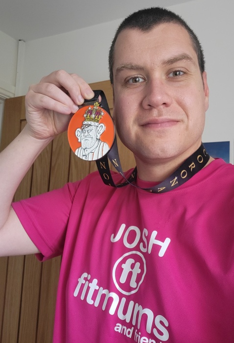 Josh smiling and wearing a medal after a race.
