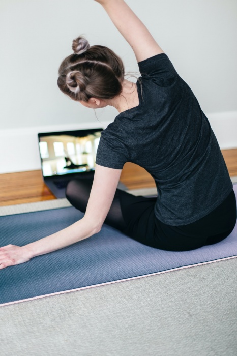 lady exercising on mat in front of laptop