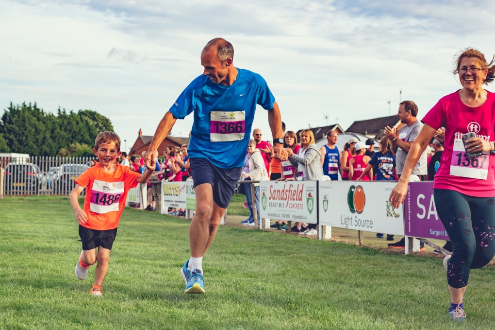 two adults and a child taking part in a fun run