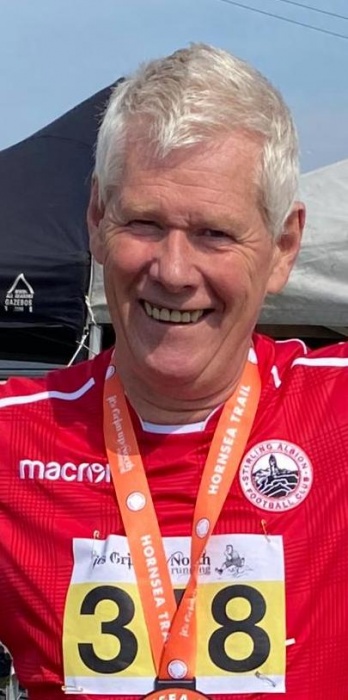 Alasdair smiling and wearing a medal after a race.