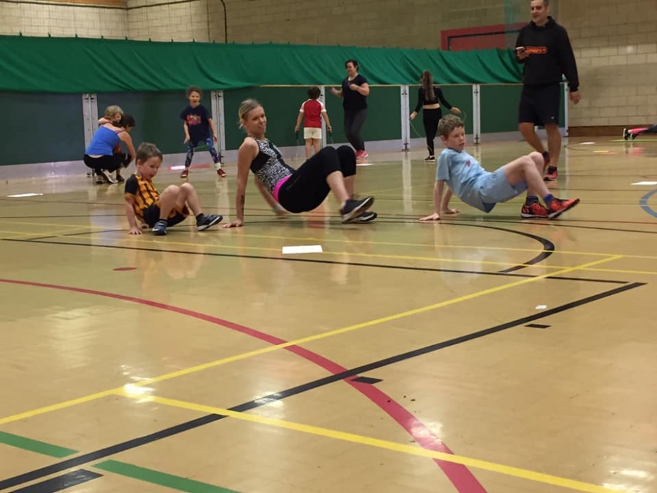 A mum and two boys working out in a sports hall