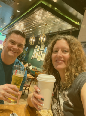 Emma and Stuart holding their drinks in the airport