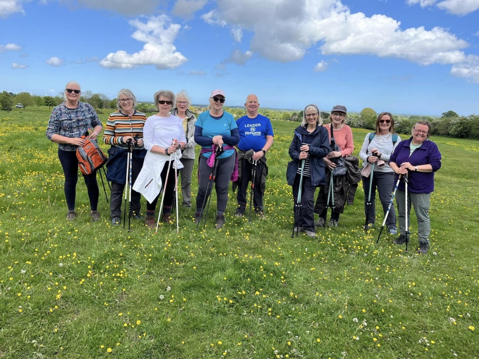A group of ladies and men holding Nordic Walking poles standing in a meadow