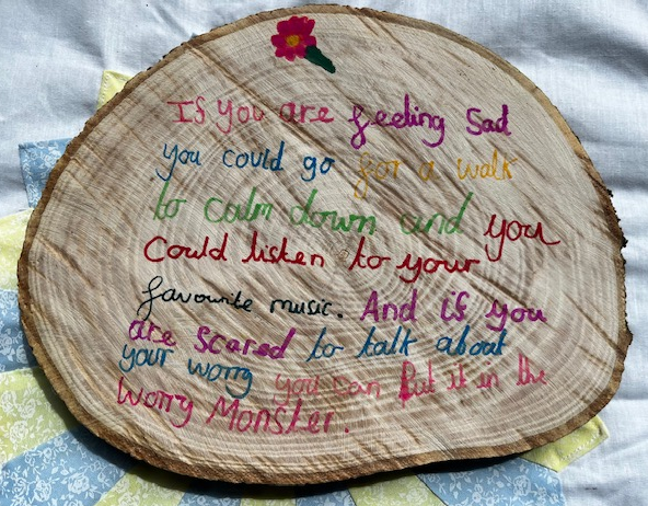 A child's writing on a wooden slice.