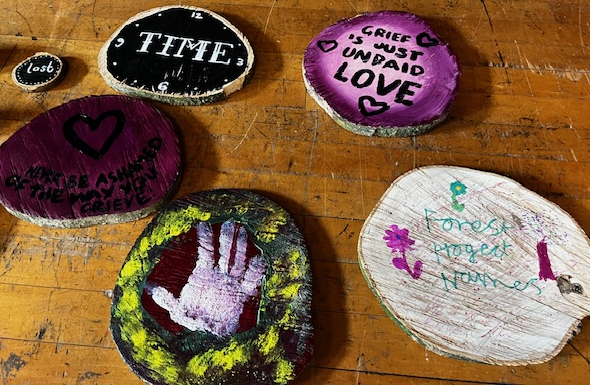 A selection of wood slices painted with children's artwork.