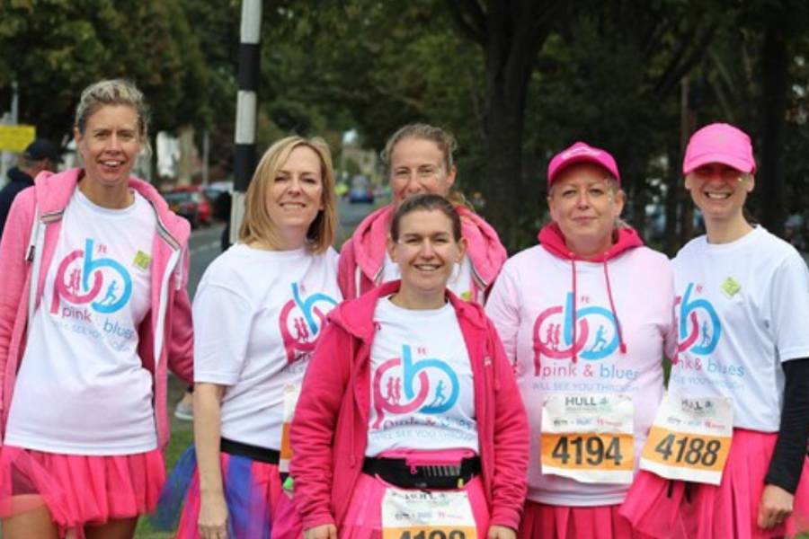 6 ladies dressed in tutus and pink hoodies smiling at the camera