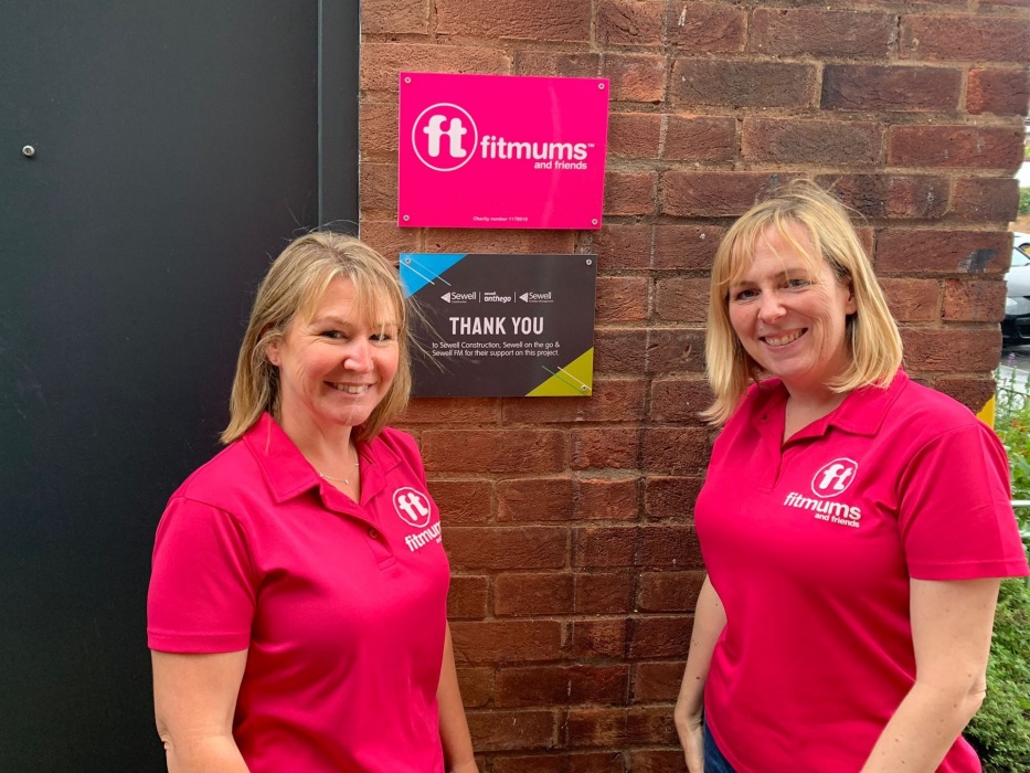 Heather and Vickie standing next to signs outside the new office door
